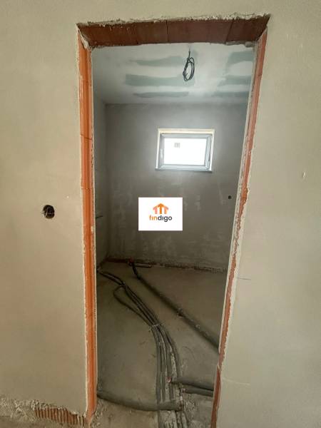 Unfinished room in a family house with a window and prepared electrical installation.