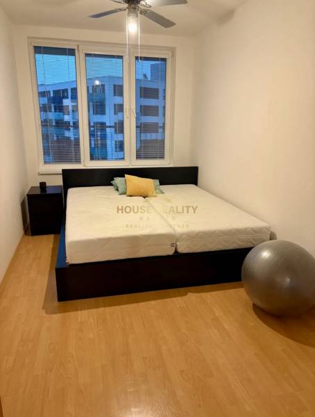 A bedroom with a bed, a nightstand, and an exercise ball in a two-room apartment.