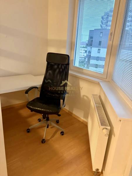A room in a 2-room apartment with an office chair, desk, and radiator.
