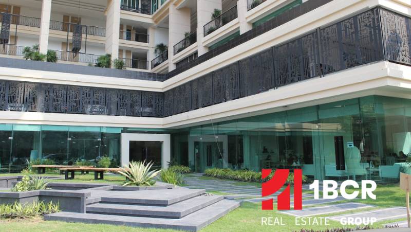 Apartment construction in Pattaya with glass facades and balconies with plants.