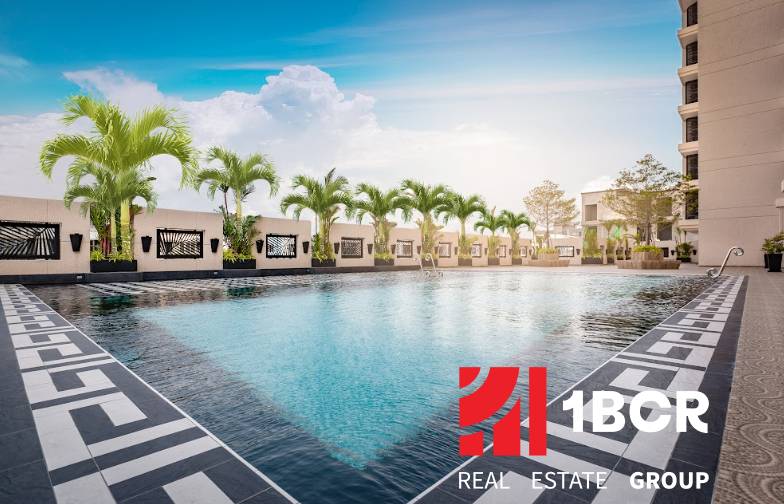 A pool with palm trees under construction in an apartment complex in Pattaya under the blue sky.