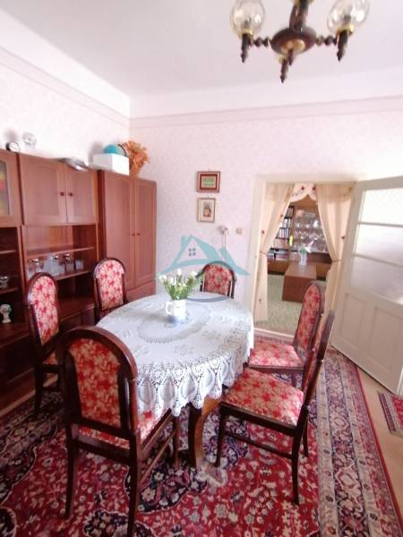 Dining room in a family house with antique furniture, a floral carpet, and light decor.
