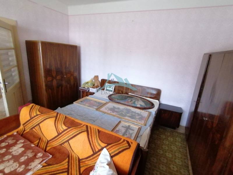 Bedroom in a family house with a bed, wardrobes, and paintings on the wall.
