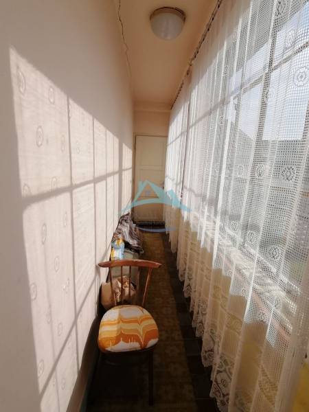 A narrow hallway with lace curtains and an armchair in a family house.