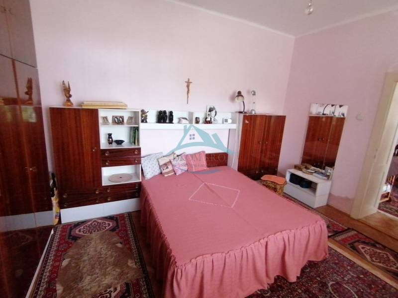 A bedroom with wooden furniture and pink bedding in a family house.