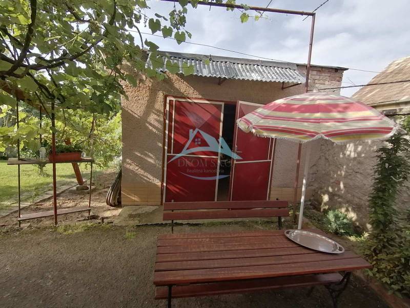 A garden by a family house in Hrkovce with a table and an umbrella.