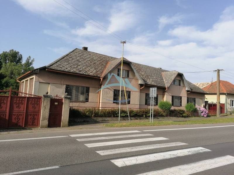 A family house in Hrkovce by the road, tiled roof, closed red gates.