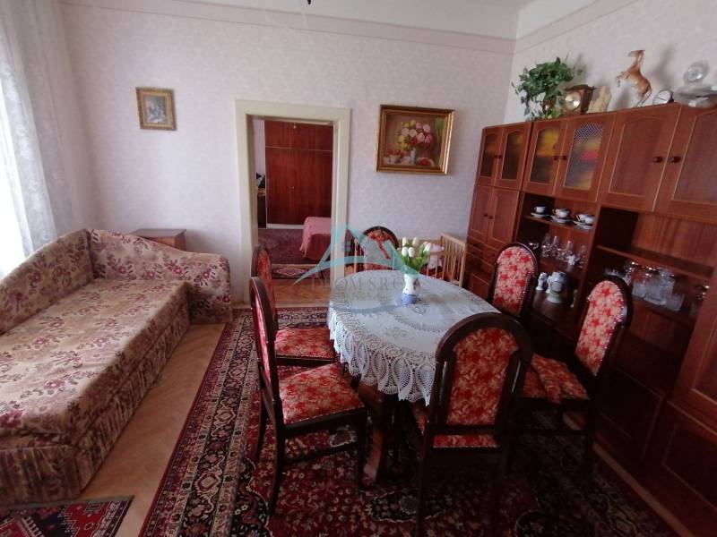 Living room in a family house with a sofa, dining table, and display cabinet.