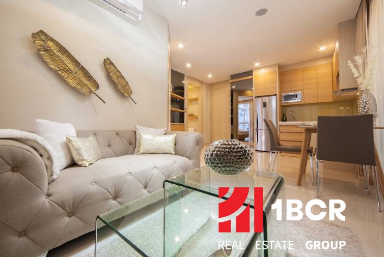 Stylish interior of a 2-room apartment with a comfortable sofa and modern kitchen equipment.