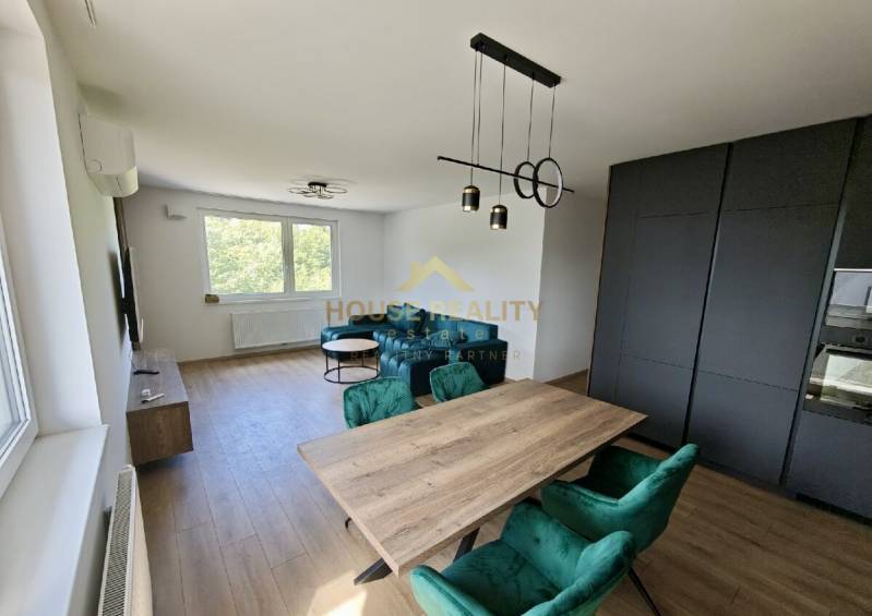 Dining room with a wooden table and green chairs in a 3-room apartment.
