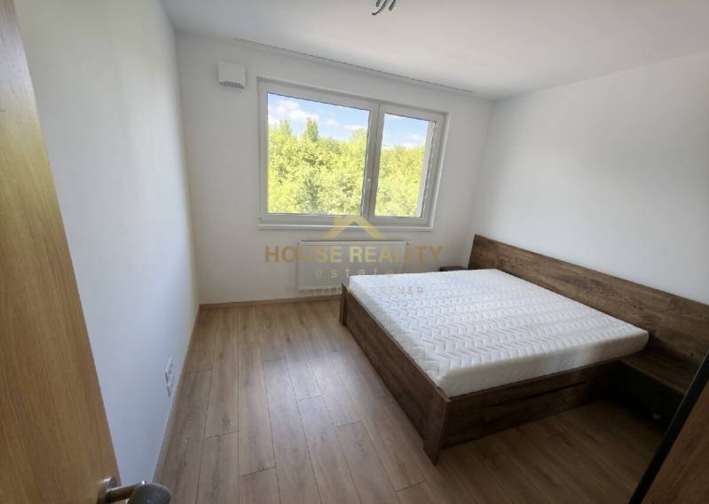 A bedroom in a 3-room apartment with a bed and a view of greenery.