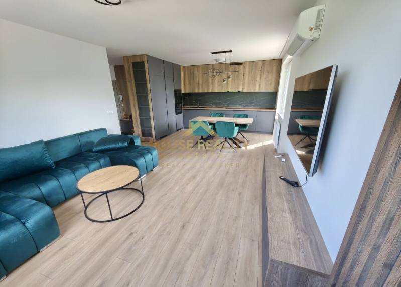 Living room and kitchen in a 3-room apartment with a turquoise sofa and a dining area.