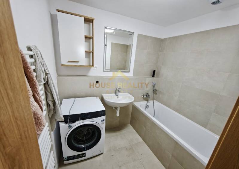 Bathroom in a 3-room apartment with a washing machine, bathtub, and sink in light shades.