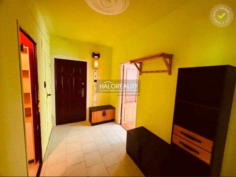 A hallway in a colorful 3-room apartment with a cabinet and a shelf.