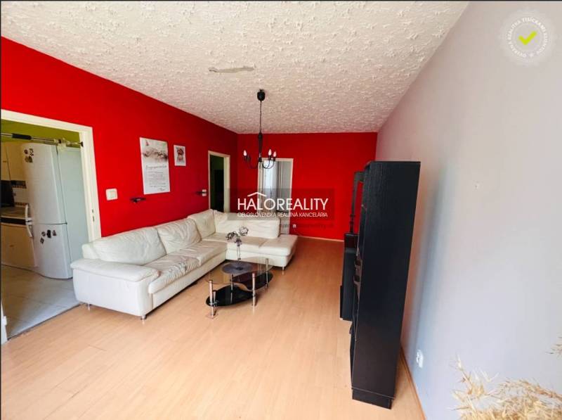 Living room in a three-room apartment with a light sofa and a red wall.