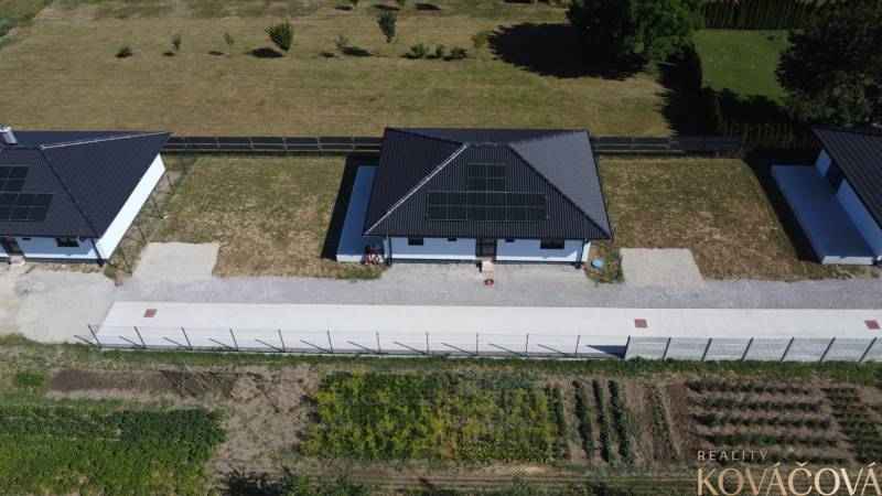 Family houses in Podlužany with solar panels, lawn, and garden.