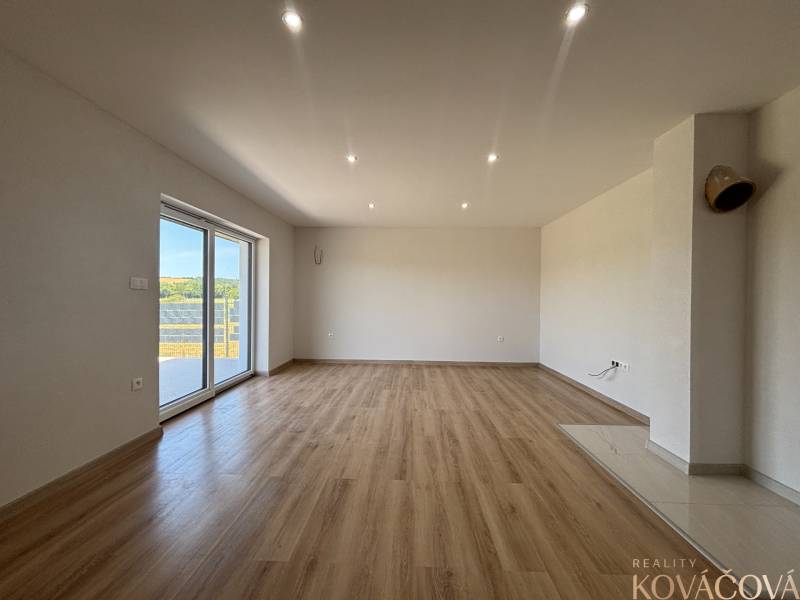 A spacious room with a wooden floor and a large window in a family house.