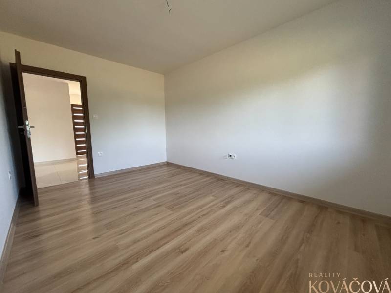 Empty room in a family house with wooden flooring and white walls.