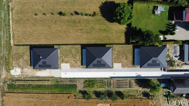 An aerial view of three family houses in Podlužany with solar panels on the roofs.