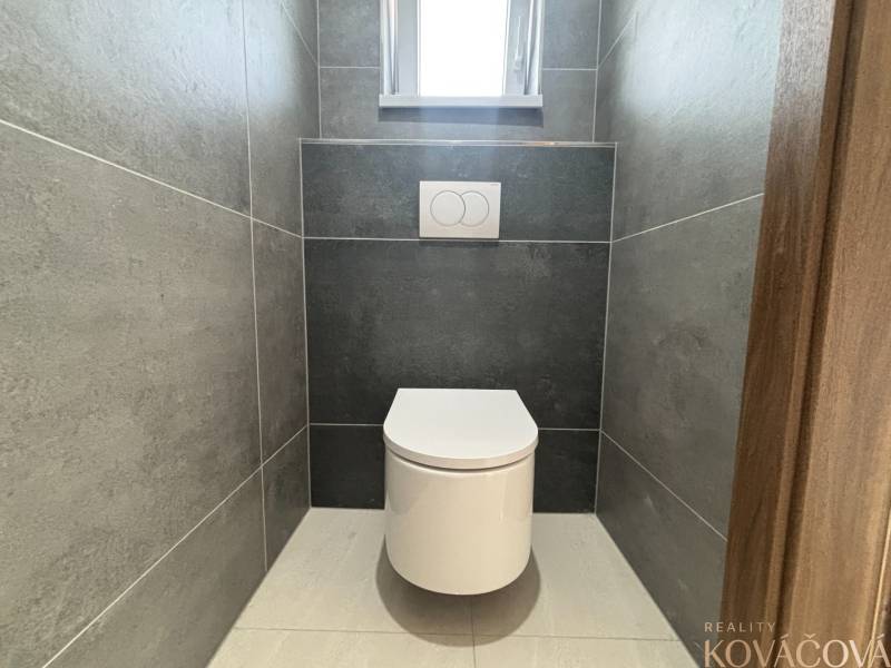 A toilet with tiles in a family house, minimalist design with gray tiles.