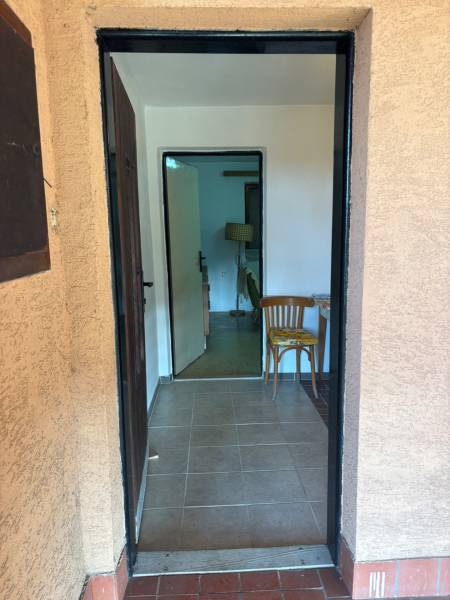 A corridor leading to a room, white interior, wooden chairs, recreational grounds.