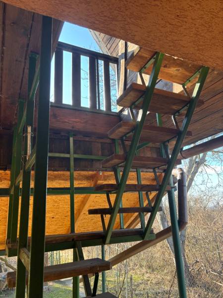 A wooden staircase to the recreational grounds, surrounded by nature, provides access to the elevated terrace.