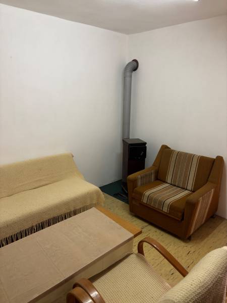A room with a fireplace, recreational plots, a comfortable sofa, an armchair, and a coffee table.
