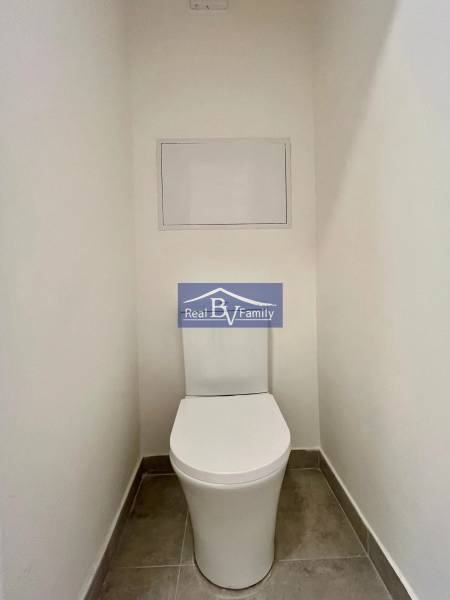 Toilet in a 2-room apartment with white walls and ceramic tiles.