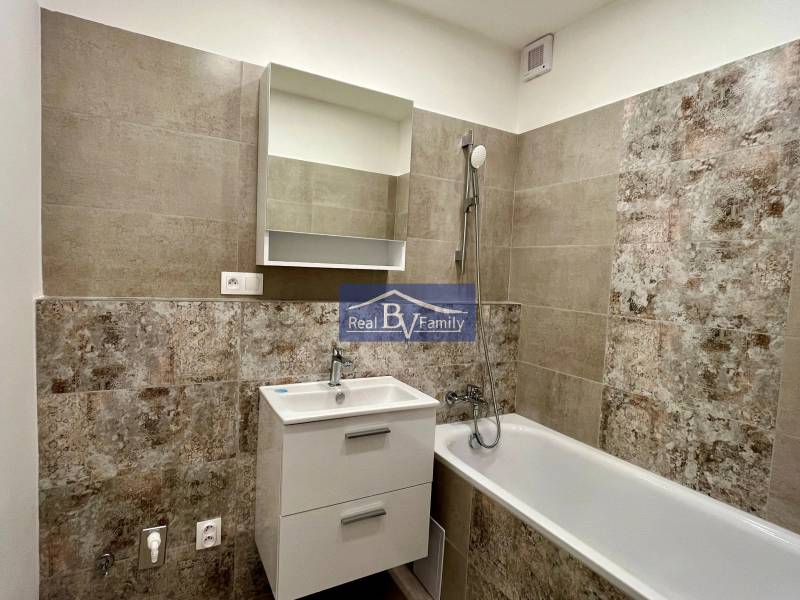 A bathroom with a bathtub, a sink, and tiles in a two-room apartment.