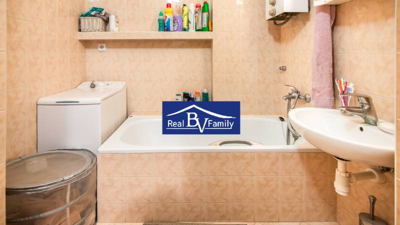 Bathroom in a studio apartment with a washing machine, bathtub, and sink.