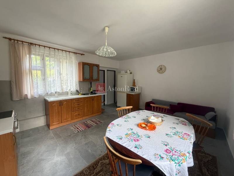 A kitchen in a family house with wooden furniture, a dining table, and a couch.