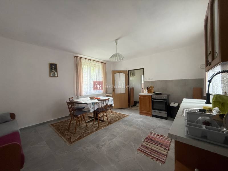 Dining room with a table and chairs, kitchen unit, and stove in a family house.