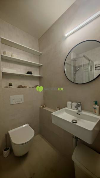 Bathroom in a studio apartment with a round mirror, sink, and toilet.
