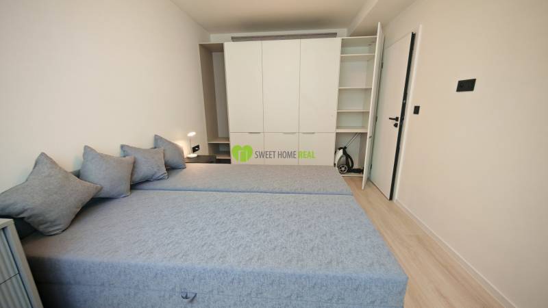 A bedroom in a one-room apartment with two beds, a built-in wardrobe, and a night lamp.
