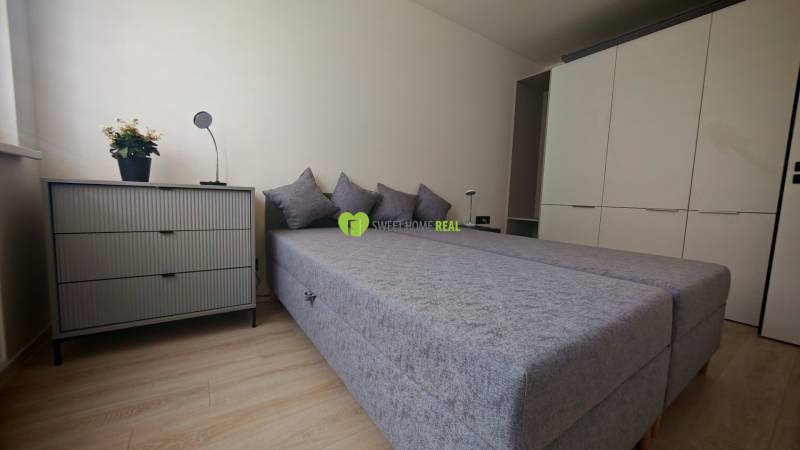 A bedroom with a bed, wardrobe, and dresser in a studio apartment.