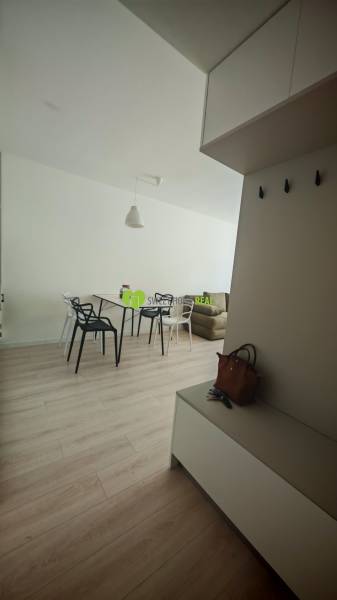 Interior of a 1-room apartment with light furniture and wooden flooring, includes a dining table.
