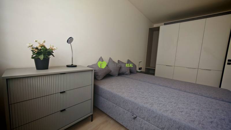 A bedroom with a double bed, wardrobe, dresser, and decorations in a studio apartment.