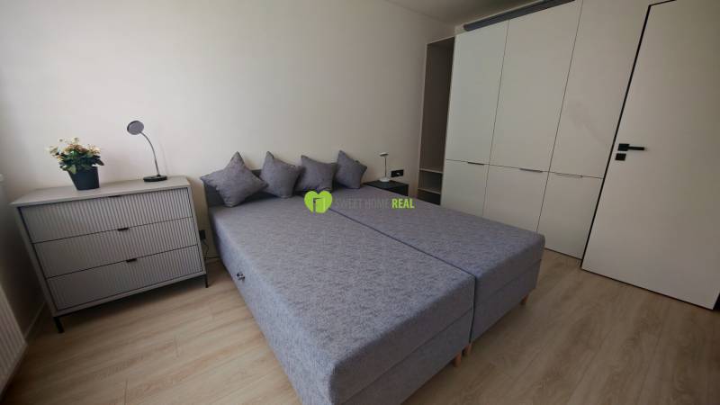 A bedroom in a one-room apartment with two beds, a chest of drawers, and a large wardrobe.