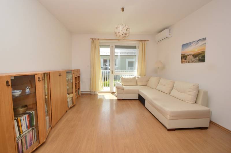 Bright living room with a sofa, bookshelf, and balcony in a 2-room apartment.