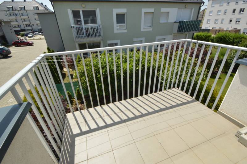 The balcony of a 2-room apartment in Rajka with a view of the garden and surrounding architecture.