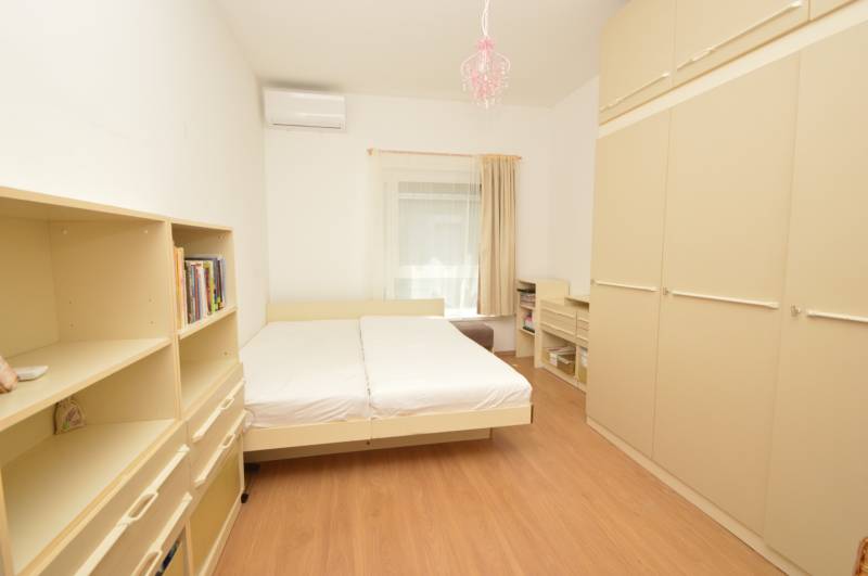 A bedroom in a 2-room apartment with a bed, shelves, and air conditioning.