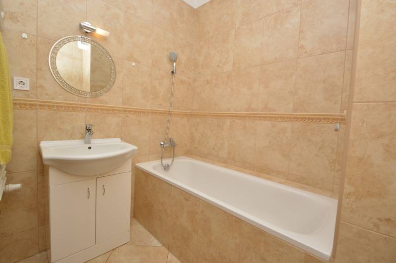Bathroom amenities in a 2-room apartment with a shower and a sink with a round mirror.