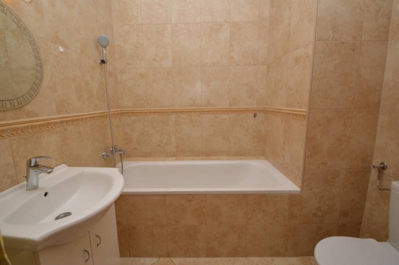 Bathroom with a bathtub, mirror, and sink in a 2-room apartment.