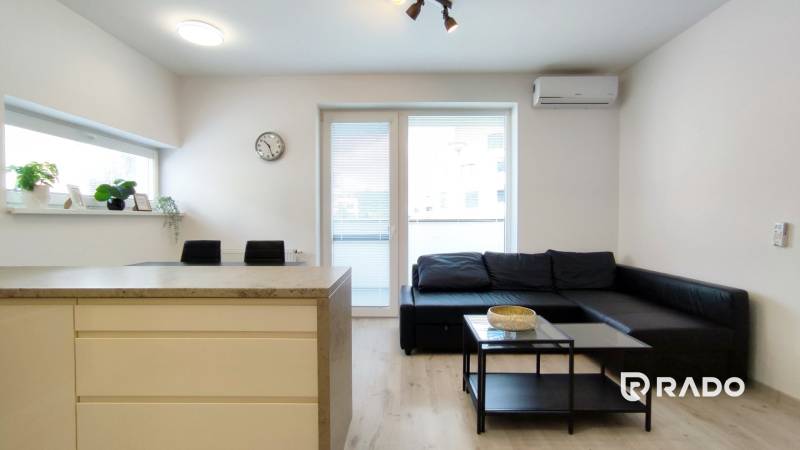 Living room in a two-room apartment with a sofa, table, and access to the balcony.