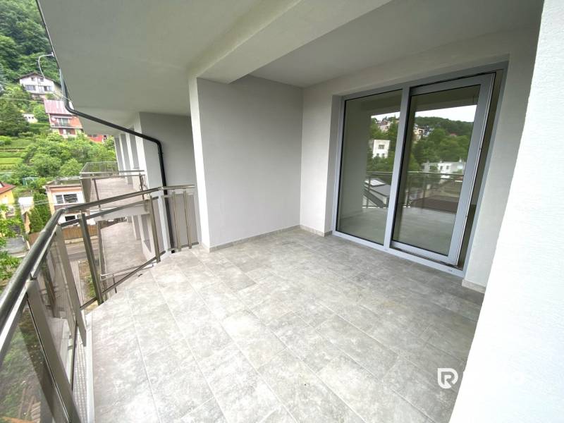 A balcony in a 2-room apartment in Rajecké Teplice with a view of greenery and surrounding buildings.