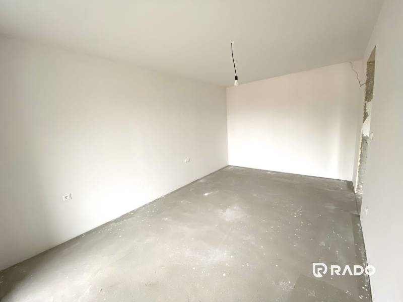 Empty room in a 2-room apartment with white walls and a concrete floor.