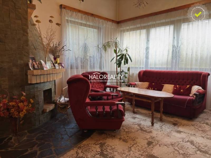 Interior of a family house with a fireplace, red sofas, and a wooden table.