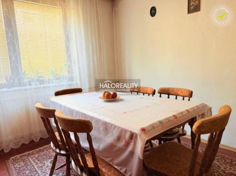 Dining room with a wooden table and chairs, decorated with curtains and a cutlery picture.