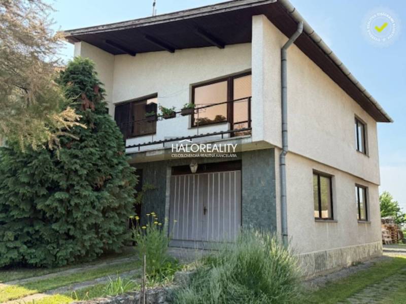 A family house in Borša with two floors, a garden, and coniferous trees.