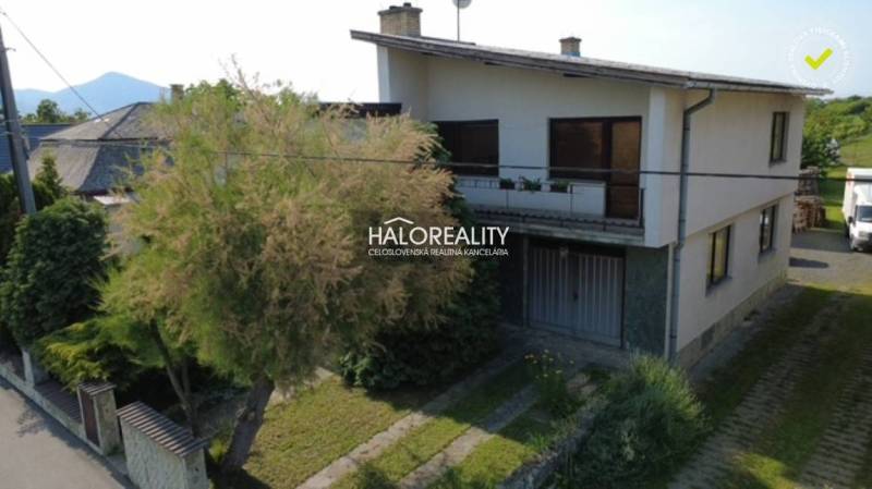 A family house in Borša, two-story, with a balcony and a landscaped yard, surrounded by greenery.